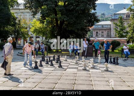 Giocatori locali di scacchi si riuniscono in Piazza della Liberazione e giocano con una scacchiera in grande scala,.Sarajevo, Bosnia ed Erzegovina Foto Stock