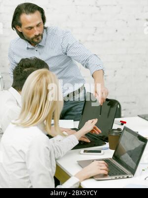 Team aziendale che si occupa di brainstorming insieme in un ufficio moderno. I colleghi discutono del nuovo progetto visualizzandolo sullo schermo nero del monitor del computer. Lavoro di squadra Foto Stock