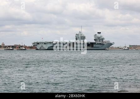 Una piccola flottiglia di rimorchiatori guida la Royal Navy portaerei HMS REGINA ELISABETTA verso l'ingresso del porto questa mattina Foto Stock