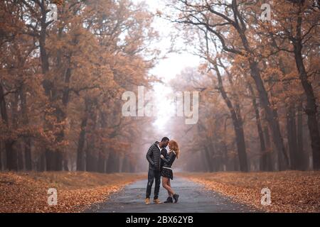 Coppia interracial che posa in autunno strada parco, uomo nero e bianco rosso donna Foto Stock