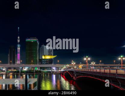 tokyo, giappone - marzo 25 2020: Vista notturna del ponte Azuma sul fiume Sumida che conduce allo Skytree di Tokyo e alla scultura olimpica a forma di fiamma dorata Foto Stock