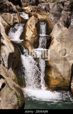 Terrazze a cascata e gradini di un sistema fluviale che scorre su terreno roccioso in un piccolo canyon Foto Stock
