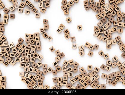 Piccole perle di legno cubico con varie lettere sparse su sfondo bianco, vista dall'alto Foto Stock