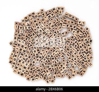 Piccole perle di legno cubico con varie lettere sparse su sfondo bianco, vista dall'alto Foto Stock