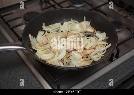 Cipolle brune affette frittura a olio su forno a gas Foto Stock
