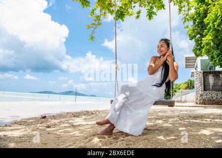 bella donna seduta su un altalena sulla spiaggia dentro Phuket Foto Stock