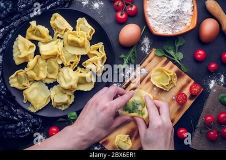 Le mani degli uomini preparano la pasta italiana con ingredienti. Concetto gastronomico Foto Stock