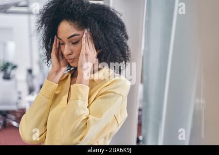 Giovane dipendente femminile moderno che ha un mal di testa Foto Stock