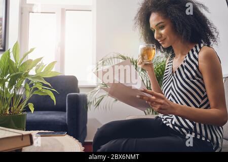 Donna d'affari che guarda attraverso i giornali durante la pausa del tè Foto Stock