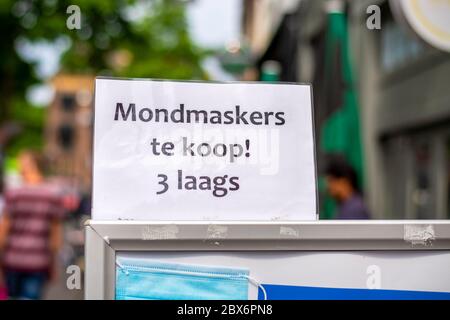 Primo piano di un cartello che annuncia in olandese che maschere mediche contro il coronavirus sono disponibili presso un negozio locale. Foto Stock