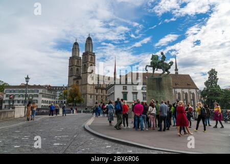 Zurigo, Svizzera - 6 ottobre 2018: Gruppo di turisti che visitano il monumento equestre di Hans Waldmann e la chiesa di Grossmünster Foto Stock