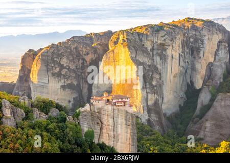 Grecia. Soleggiata serata estiva in una valle di montagna. Un monastero di pietra in cima a una scogliera Foto Stock