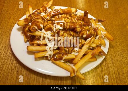 Una versione di poutine, un piatto canadese popolare. È solitamente fatto con le patatine fritte coperte con sugo di carne e i caglidi formaggio. Foto Stock