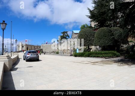 San Marino, Italia, 09 maggio 2019: Auto in avvicinamento al parcheggio e punto di osservazione in cima alla stazione della funivia di San Marino in blu giornata di sole Foto Stock