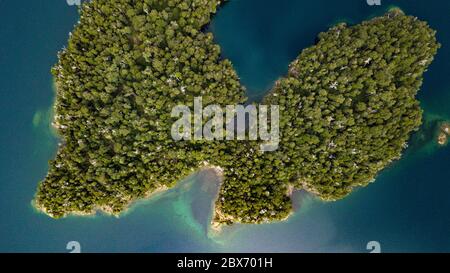 Vista aerea dall'alto dell'isola a forma di longa sul lago di acque blu scuro a Patagonia, Argentina. Isola con alberi verdi. Foto Stock