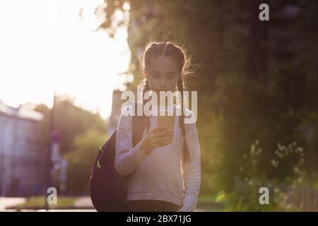 Bambino che usa lo smartphone al tramonto Foto Stock