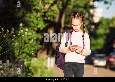 Bambino che usa lo smartphone al tramonto Foto Stock