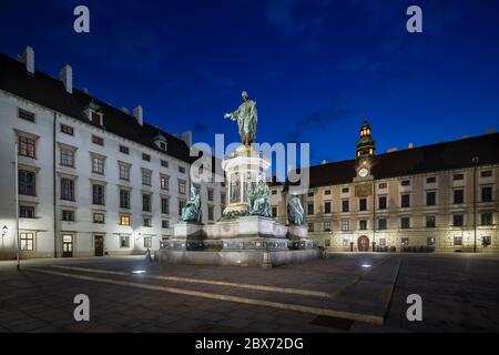 Ampio cortile interno dell'Hofburg a Vienna, in Austria di notte con cielo blu profondo e la statua del Kaiser Franz. Foto Stock