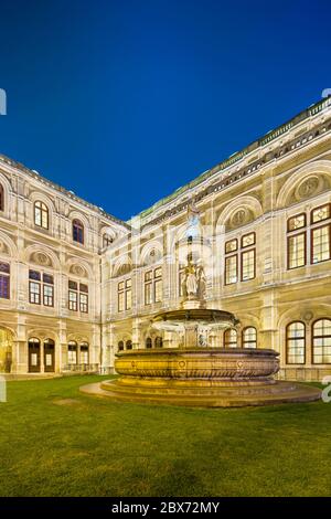 Vista laterale e fontana dell'Opera di Stato di Vienna (Wiener Staatsoper) di notte in Austria. Foto Stock