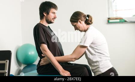 Fisioterapista che si esercita con persone disabili su un tavolo terapeutico. Foto Stock