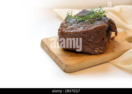 Pezzo di manzo arrosto brasato in vino rosso con guarnitura al timo su un tagliere, preparazione tipica per boeuf bourguignon, il fondo leggero è fadi Foto Stock