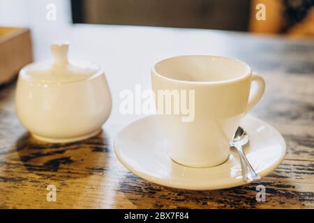 Caffè fresco aromatico in una tazza bianca. Espresso in una piccola tazza bianca e una ciotola di zucchero in un caffè estivo. Caffè fresco e fragrante in un ristorante Foto Stock