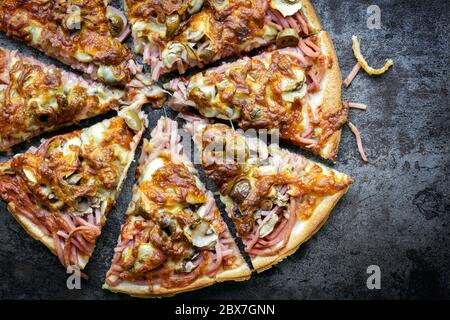 Pizza, a fette. Vista dall'alto su ardesia scura. Gustosa capricciosa italiana tradizionale. Foto Stock