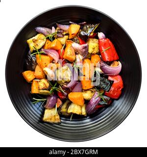 Verdure arrosto su piatto nero. Vista dall'alto, isolata su bianco. Foto Stock