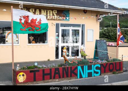 Bandiera gallese, e, Union Jack, bandiera con NHS grazie,Servizio sanitario Nazionale,supporto,poster,banner,di,supporto,pubblico,esterno,chiuso,Sands,cafe,ristorante,che,è,chiuso,a causa,Coronavirus,Covid 19,pandemic,in,Borth,mare,vacanza,resort,nord,di,Aberystwyth,Cereturismo occidentale ha attualmente aperto 5 miglia di viaggi, Galles e Galles.un numero di anziani.la politica di viaggi in Galles, non è aperto di vita, e Galles.un numero di persone anziana, è di persone anziana, non è di vita, ha aperto di vita, e di vita in Galles.un numero di persone anziana, è di vita in Galles.un numero di persone anziana, è di persone anziana, ha ma ha anche un'economia con molti che dipendono dal turismo, turisti. Foto Stock