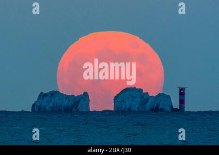 The Needles, Isola di Wight, Regno Unito. 5 giugno 2020. Regno Unito Meteo. La luna piena di fragole sorge da dietro gli aghi sull'isola di Wight al crepuscolo visto da Mudeford in Dorset. Immagine: Graham Hunt/Alamy Live News Foto Stock