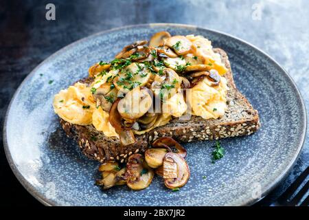 Uova strapazzate e funghi su pane tostato integrale. Foto Stock