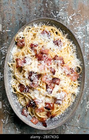 Spaghetti carbonara, vista dall'alto, in piatto ovale su tavola rustica in legno. Foto Stock