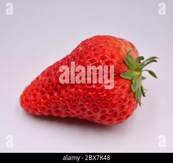 Una fragola fresca con un piccolo lavandino sulla superficie con fondo bianco Foto Stock