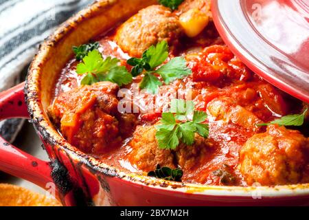 Polpette di pollo in salsa di pomodoro, cucinando in casseruola rossa. Foto Stock