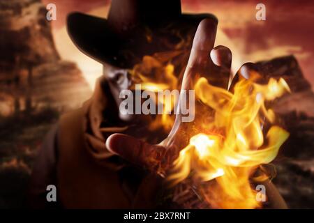 Foto di un cowboy demoniaco del cranio in cappello che getta incantesimo di fuoco con il suo braccio su uno sfondo desertico tramonto. Foto Stock