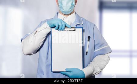 Foto di un medico in completo vestito e guanti di gomma che tengono una compressa con carte vuote in entrambe le mani. Foto Stock