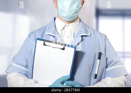 Foto di un assistente di laboratorio in completo abito e guanti di gomma che tengono una compressa con carta vuota in una mano. Foto Stock