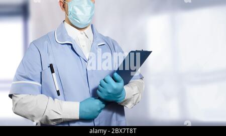 Foto di un assistente di laboratorio in completo abito e guanti di gomma che tengono un tablet con carta vuota in entrambe le mani. Foto Stock