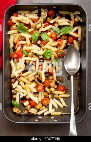 Melanzane, peperoncino e pomodoro, in una teglia. Guarnito con basilico. Foto Stock
