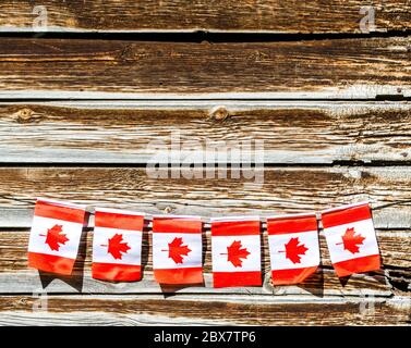 Bandiere canadesi in miniatura stese lungo una corda sulla parete esterna di un vecchio fienile con spazio per la copia Foto Stock