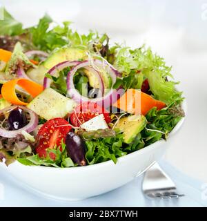 Insalata in ciotola bianca. Verdure miste con olive nere, pomodori e un sacco di verdure. Foto Stock