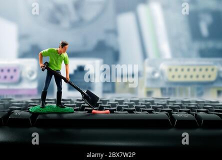 Foto di un giocattolo in miniatura con pala che lavora sui tasti della tastiera del computer. Foto Stock