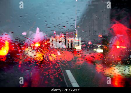 Ingorgo stradale causato da un incidente su una strada bagnata. Vista attraverso un parabrezza piovoso fino alla carreggiata Foto Stock