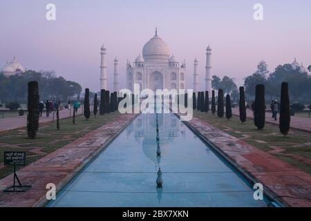 Taj Mahal e piscina riflettente in nebbia all'alba ad Agra, India Foto Stock