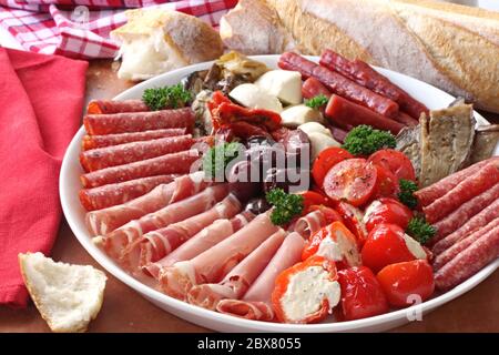 Piatto di antipasto, con pane croccante. Un miscuglio di salame, prosciutto, bocconcini, peperoni alla griglia ripieni di formaggio di capra, melanzane, pomodori, Foto Stock