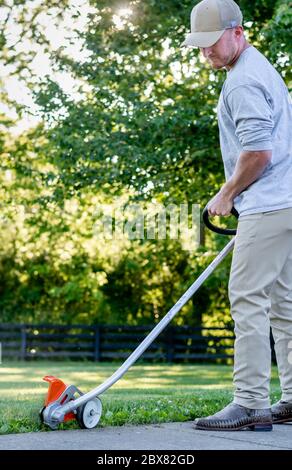 Uomo caucasico che usa un rasaerba/trimmer in Kentucky Foto Stock