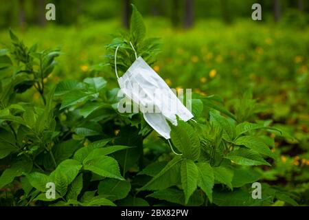 maschera medica su una filiale. Le maschere contaminate vengono gettate fuori durante la quarantena, lo scoppio di covid-19. Inquinamento ambientale, natura Foto Stock