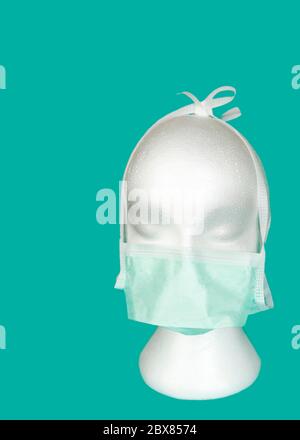 Testa manichino in polistirolo bianco con maschera chirurgica, su sfondo teale. Concetto di prevenzione delle infezioni durante una stagione di malattie respiratorie Foto Stock