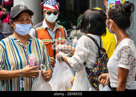 Volontari con maschere facciali che danno cibo libero durante la pandemia di Covid, Bangkok, Thailandia Foto Stock