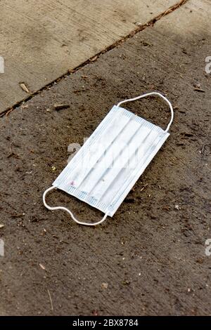 Maschera chirurgica scartata per la protezione dei germi. I dispositivi di protezione individuale (PPE) sono la nuova norma. Foto Stock